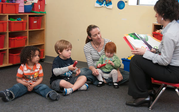 an educator reading to 3 small children